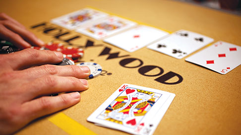 hands grabbing chips, cards on tan table