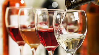 Four wine glasses, wine being poured into them