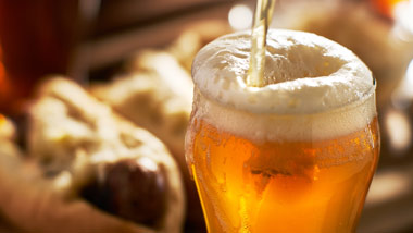 beer being poured with bratwurst sandwich in background